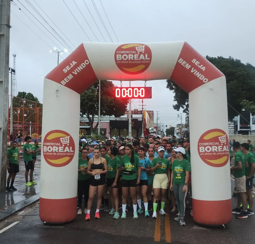 Largada de uma corrida de rua: corredores de camisa verde reunidos sob um arco inflável com a marca Comercial Boreal e a frase “Seja bem-vindo”.